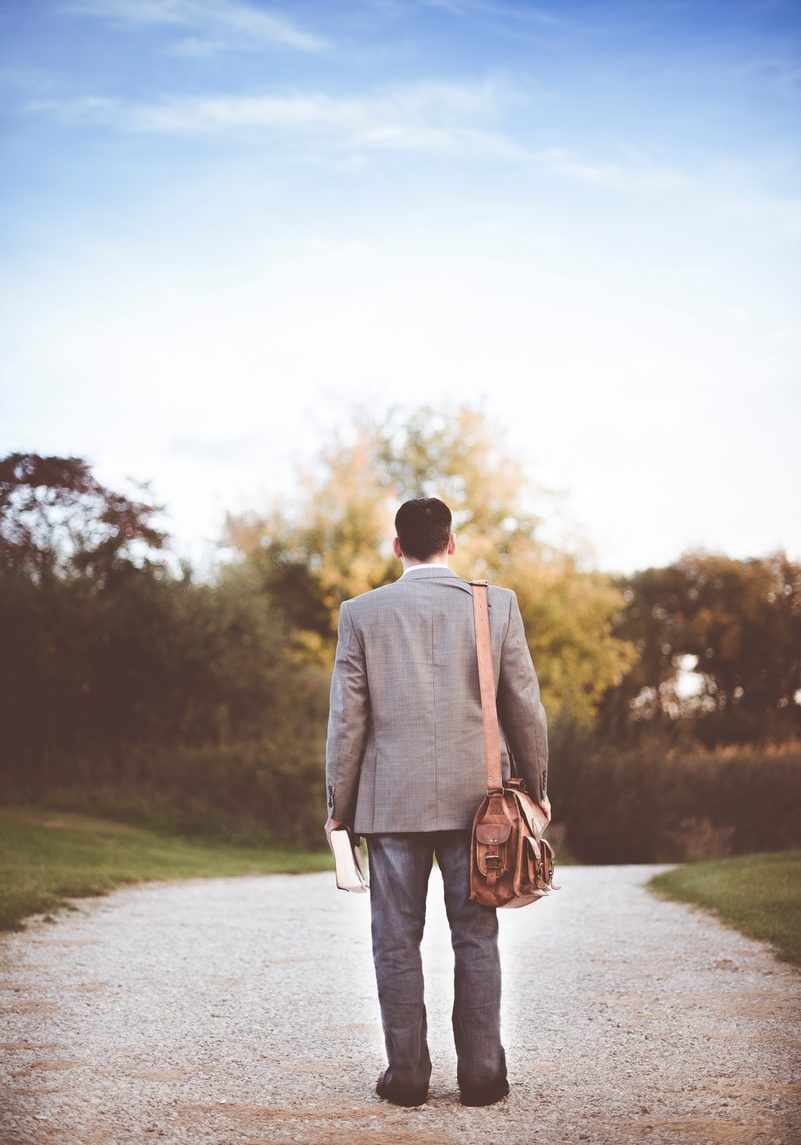 man wearing gray coat standing near road during daytime